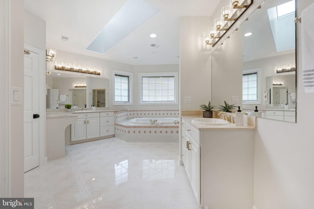 bathroom with tiled bath, vanity, and a skylight