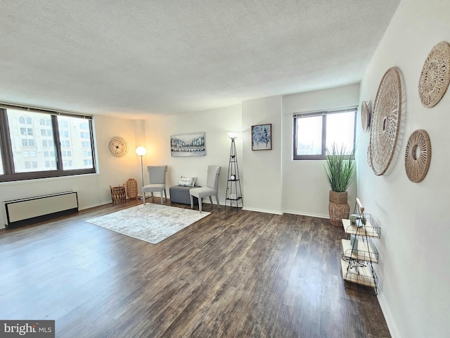 unfurnished room featuring radiator heating unit, a textured ceiling, and dark hardwood / wood-style floors