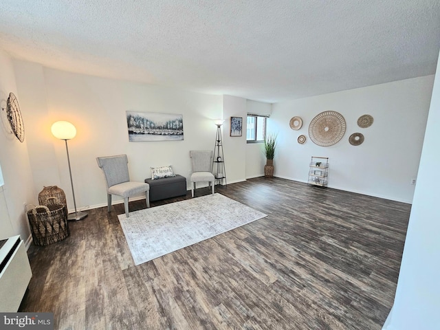 living area featuring a textured ceiling and dark hardwood / wood-style flooring