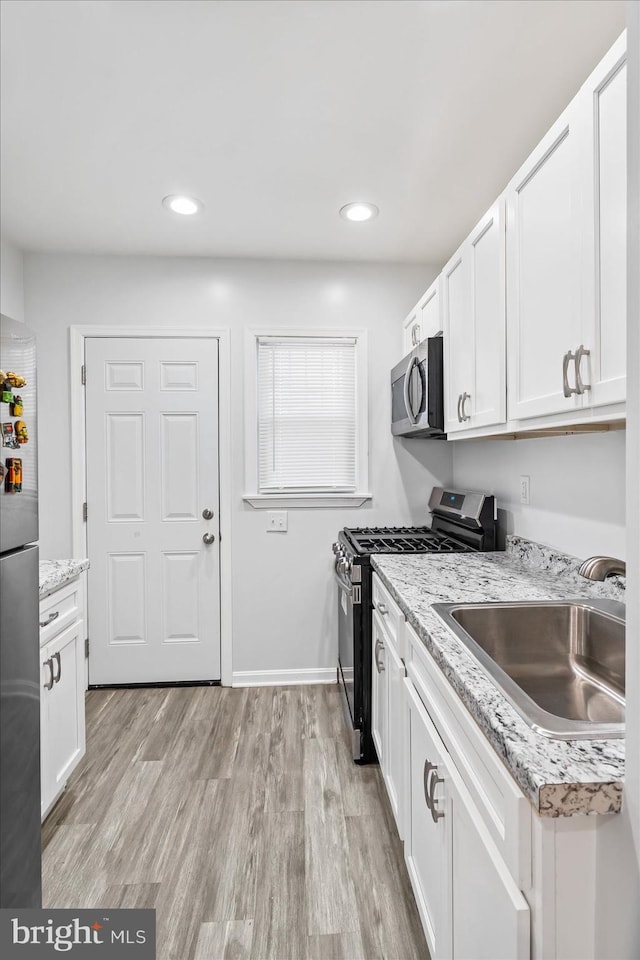 kitchen featuring white cabinetry, sink, light hardwood / wood-style flooring, and appliances with stainless steel finishes