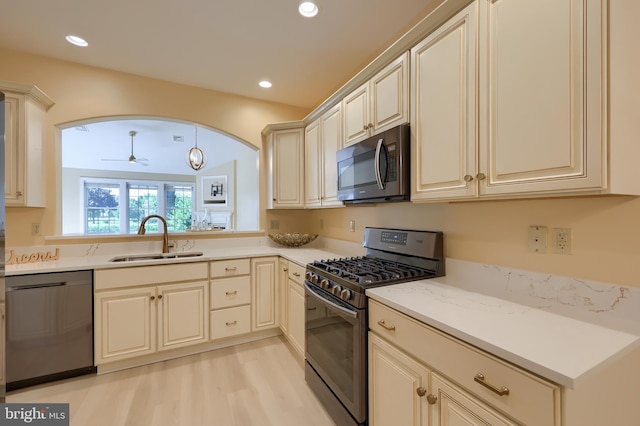 kitchen with ceiling fan, sink, light hardwood / wood-style flooring, cream cabinets, and appliances with stainless steel finishes