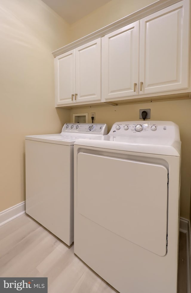 laundry area featuring separate washer and dryer, cabinets, and light hardwood / wood-style floors