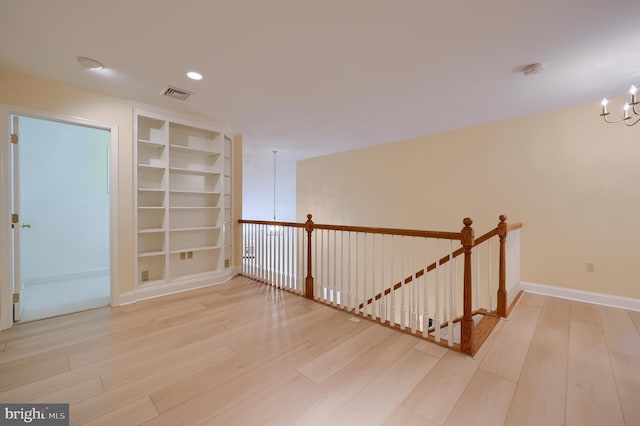 unfurnished room featuring a chandelier, light hardwood / wood-style floors, and built in features