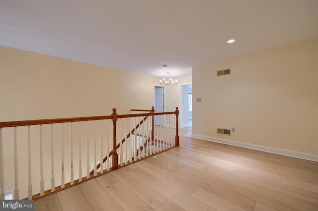 spare room featuring light wood-type flooring and a chandelier