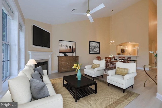 living room with ceiling fan with notable chandelier, vaulted ceiling, and light hardwood / wood-style flooring