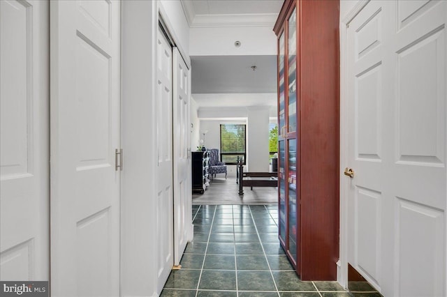 corridor with dark tile patterned flooring and ornamental molding