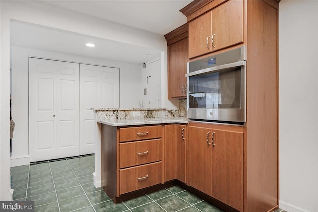 kitchen with kitchen peninsula, dark tile patterned flooring, and oven