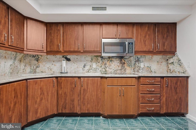 kitchen with decorative backsplash, sink, and dark tile patterned floors