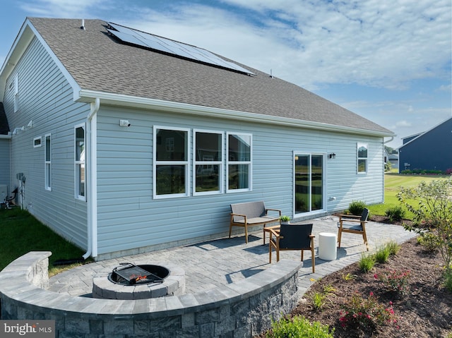 rear view of house with a patio, a fire pit, and solar panels