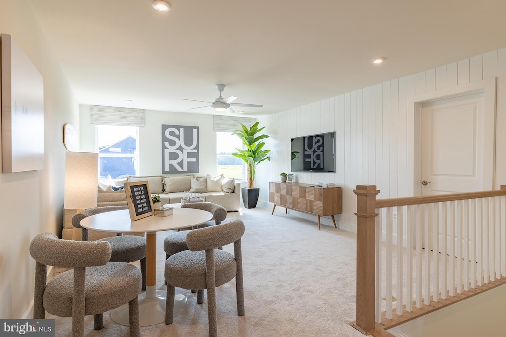 carpeted dining room featuring ceiling fan and wooden walls