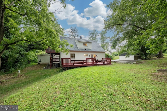 back of property with a lawn, an outbuilding, and a deck