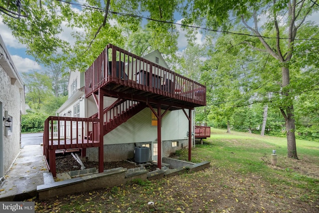 view of side of home featuring a lawn, a deck, and central air condition unit