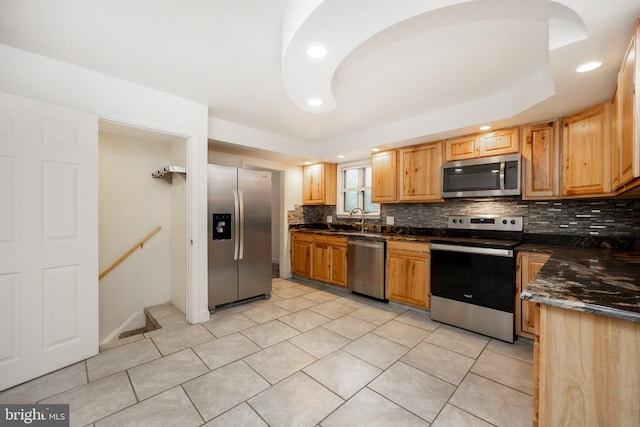 kitchen with light tile patterned floors, sink, appliances with stainless steel finishes, and dark stone counters