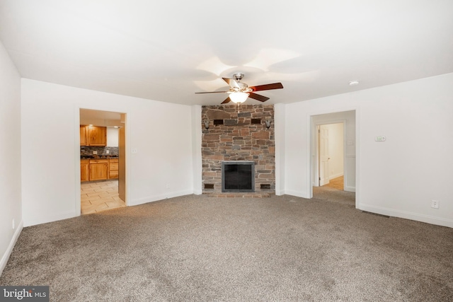 unfurnished living room with ceiling fan, a fireplace, and light colored carpet