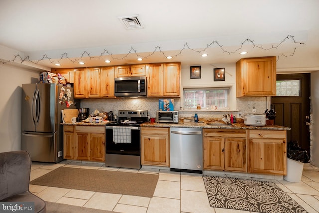 kitchen featuring stainless steel appliances, light stone counters, and light tile patterned flooring