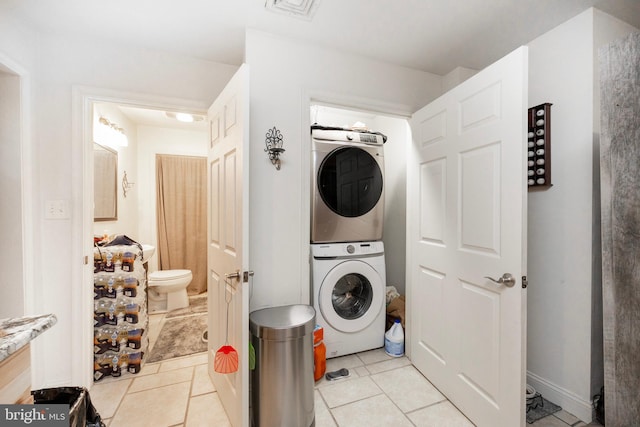 laundry room with light tile patterned flooring and stacked washer / drying machine