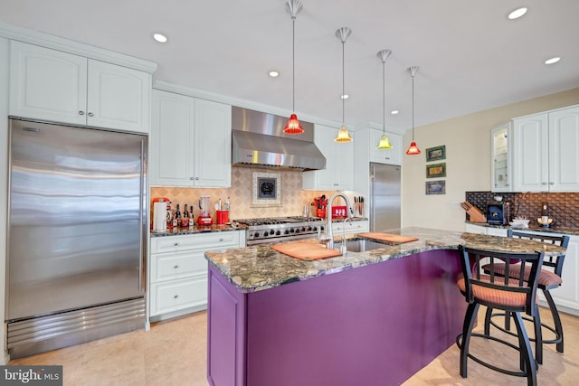 kitchen with appliances with stainless steel finishes, dark stone countertops, ventilation hood, and white cabinets