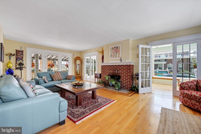 living room with a brick fireplace, french doors, hardwood / wood-style floors, and a wealth of natural light