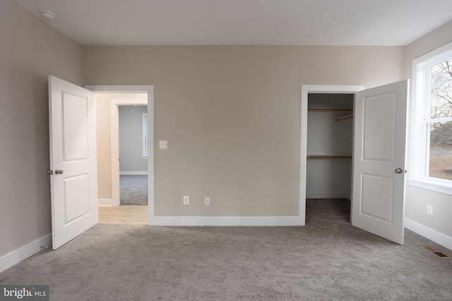 unfurnished bedroom with light carpet, a closet, and a walk in closet