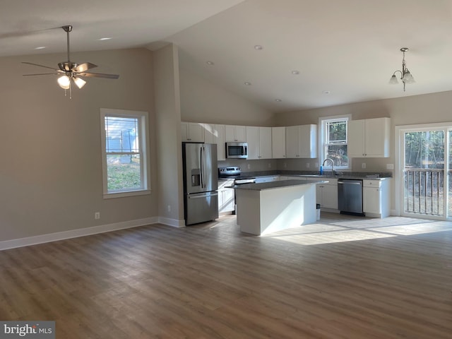 kitchen with wood-type flooring, a kitchen island, high vaulted ceiling, stainless steel appliances, and white cabinets