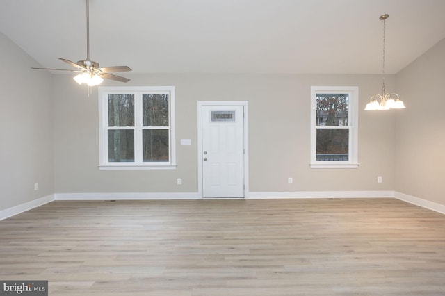 spare room with ceiling fan with notable chandelier, lofted ceiling, and light hardwood / wood-style floors