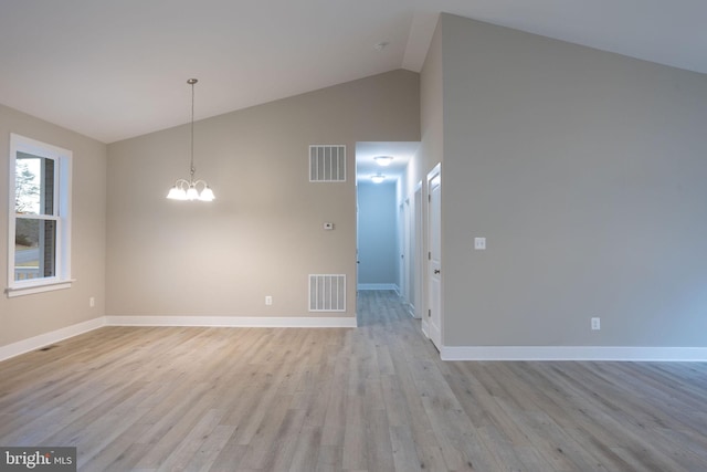 empty room with a notable chandelier, high vaulted ceiling, and light hardwood / wood-style flooring