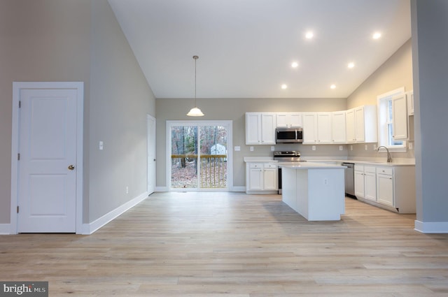 kitchen with stainless steel appliances, pendant lighting, white cabinets, and light wood-type flooring