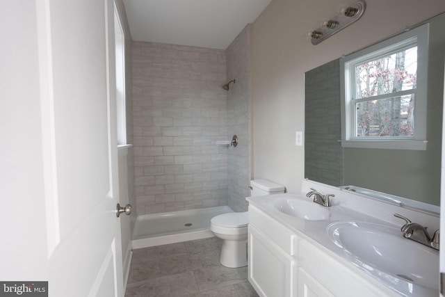 bathroom with a tile shower, vanity, toilet, and tile patterned floors