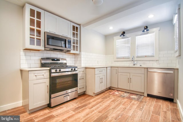 kitchen featuring sink, tasteful backsplash, light hardwood / wood-style flooring, and stainless steel appliances