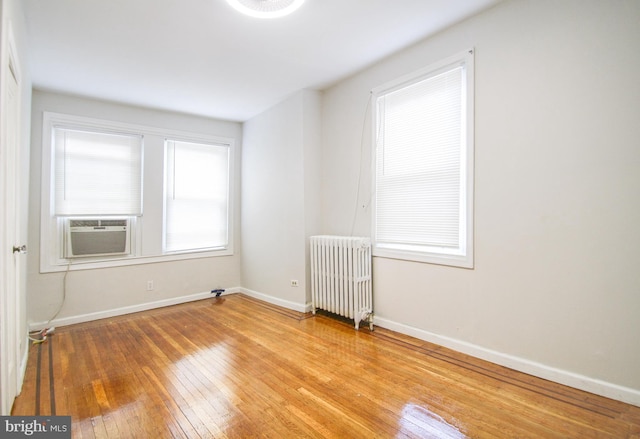 empty room featuring light hardwood / wood-style flooring, radiator heating unit, and cooling unit