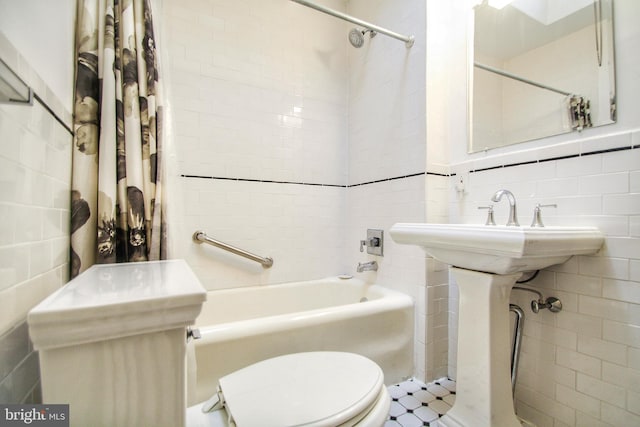 bathroom with tile walls, shower / tub combo with curtain, and toilet