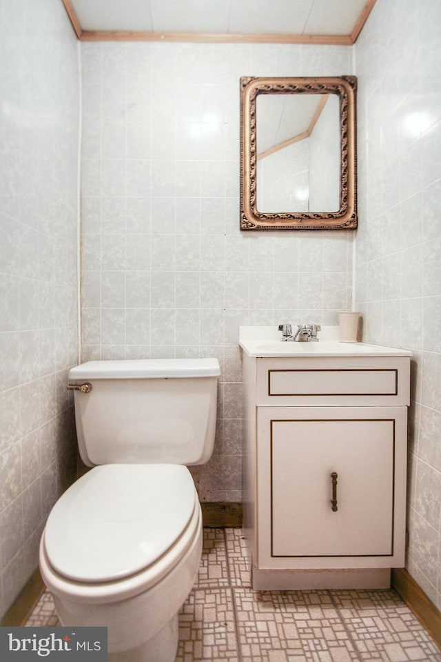 bathroom with tile patterned floors, toilet, tile walls, and vanity