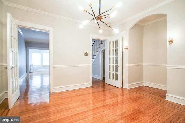 spare room featuring a notable chandelier, french doors, crown molding, and hardwood / wood-style floors