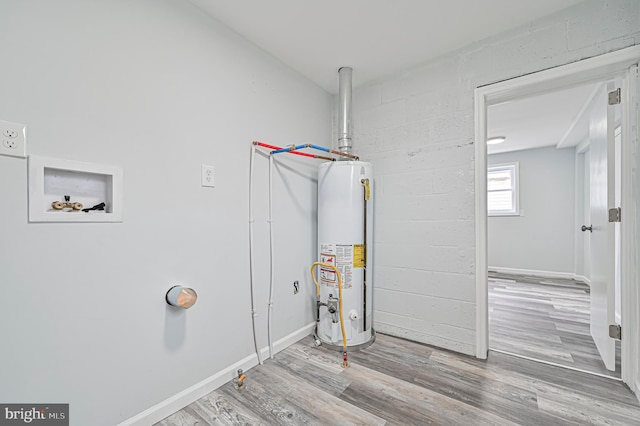 washroom with water heater, hookup for a washing machine, and wood-type flooring