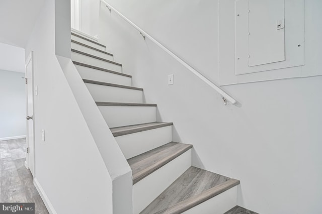 stairs with light hardwood / wood-style floors and electric panel