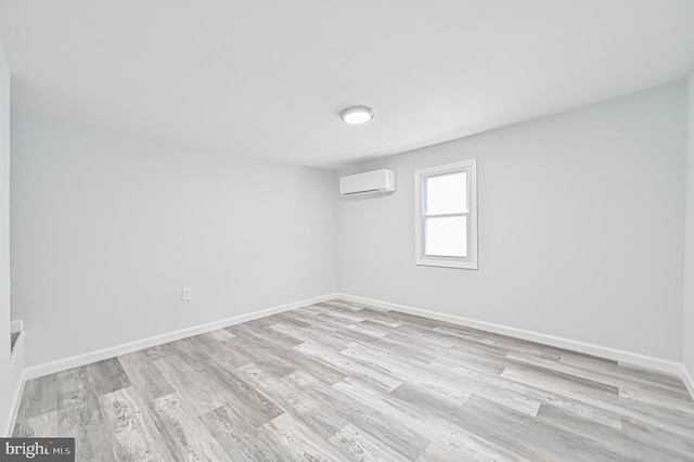 empty room with a wall mounted AC and light wood-type flooring