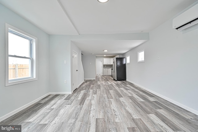 unfurnished living room with a wall mounted AC and light hardwood / wood-style floors