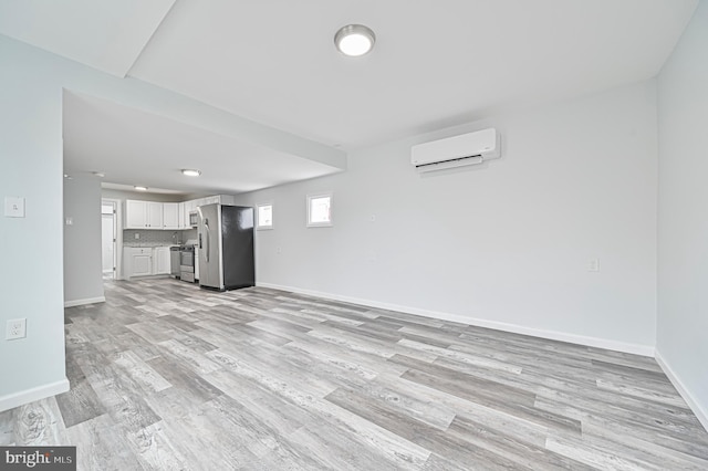 unfurnished living room featuring an AC wall unit and light wood-type flooring