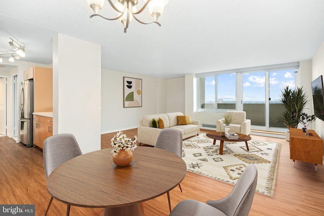 dining space with floor to ceiling windows, light wood-type flooring, a textured ceiling, and a chandelier