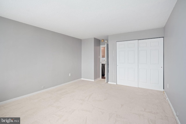 unfurnished bedroom featuring light carpet, a closet, and a textured ceiling