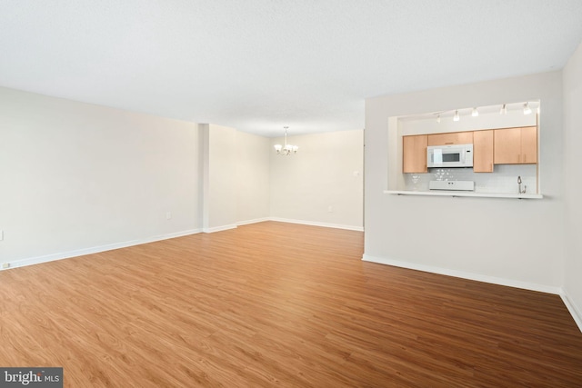 unfurnished living room featuring a chandelier and light hardwood / wood-style flooring