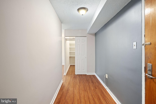 corridor featuring a textured ceiling and light hardwood / wood-style flooring