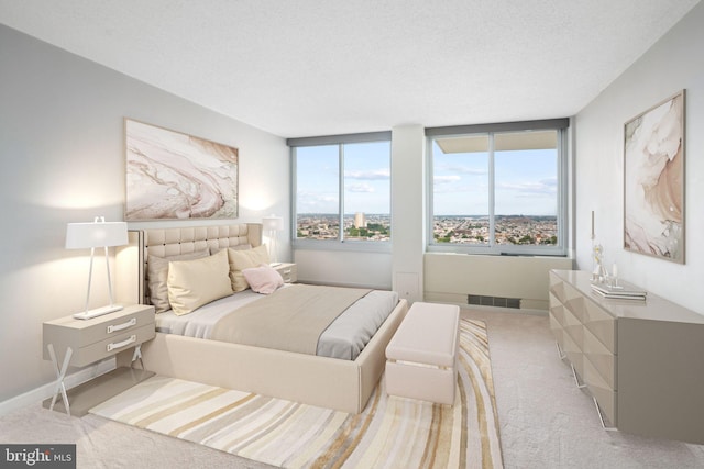 bedroom with light colored carpet and a textured ceiling