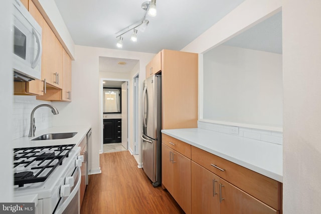 kitchen with sink, light brown cabinets, tasteful backsplash, light hardwood / wood-style floors, and white appliances