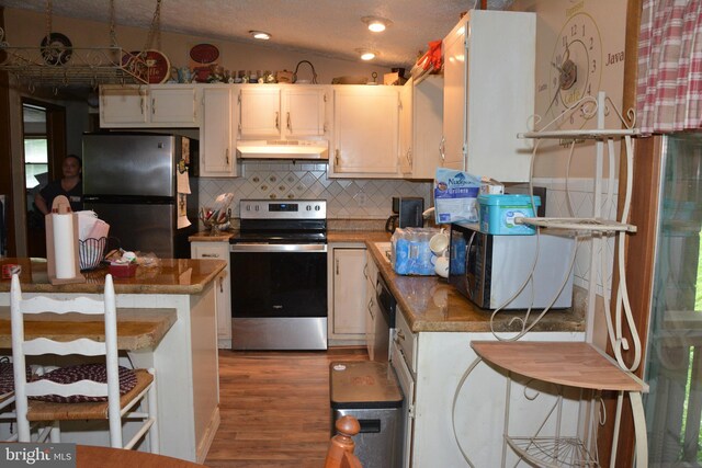 kitchen featuring lofted ceiling, dark wood-type flooring, white cabinets, decorative backsplash, and appliances with stainless steel finishes