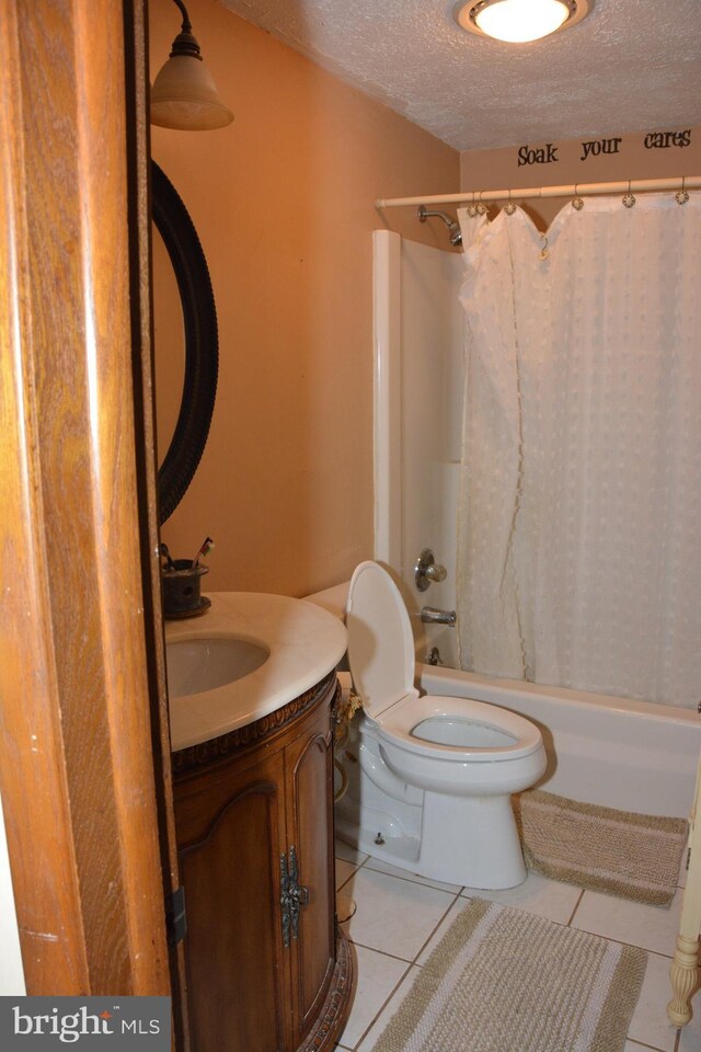 full bathroom featuring tile patterned flooring, a textured ceiling, toilet, vanity, and shower / tub combo