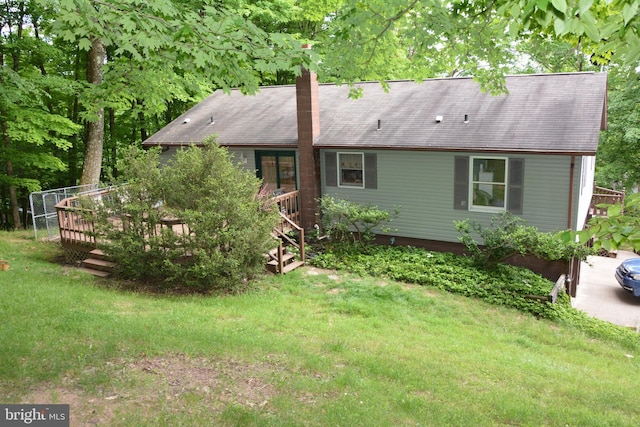 back of house featuring a lawn and a wooden deck