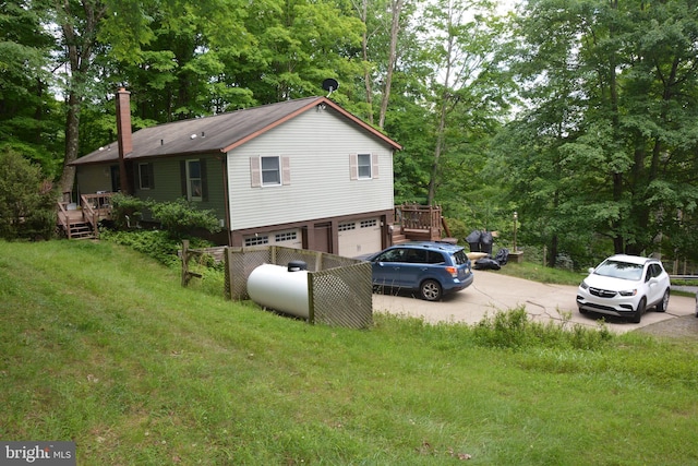 view of side of property featuring a yard, a deck, and a garage