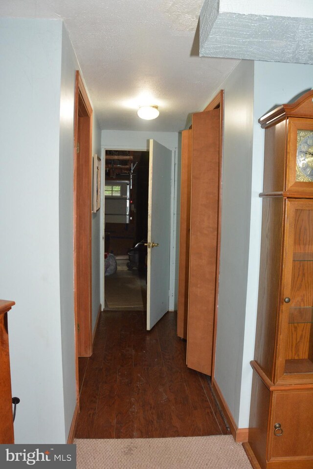 hallway featuring dark hardwood / wood-style floors and a textured ceiling