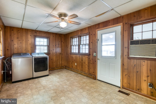 laundry area with wood walls, washing machine and clothes dryer, light tile patterned floors, and ceiling fan